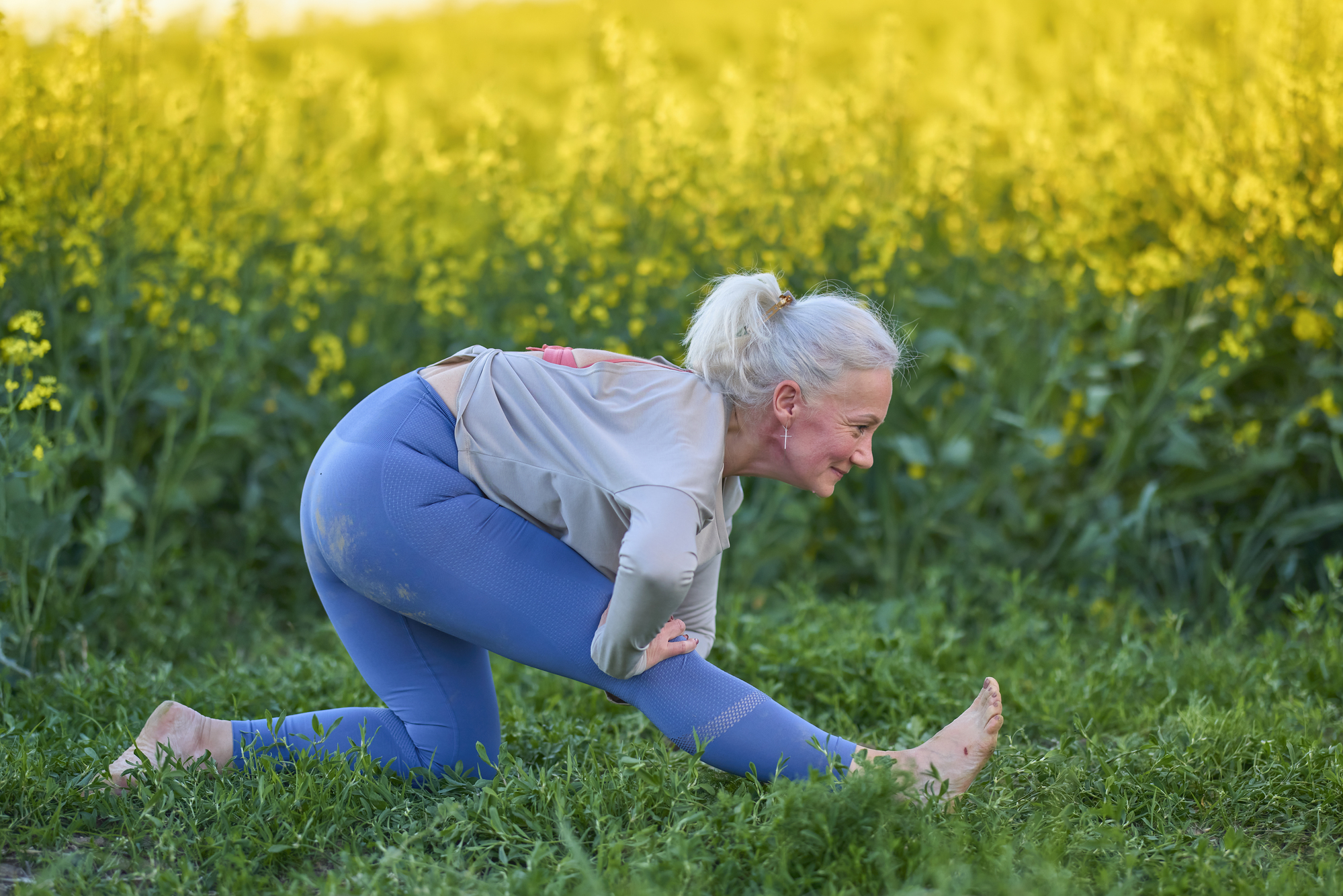 Older woman stretching outside in the grass